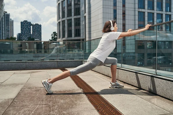 Passar mogen kvinna i hörlurar som tränar på tak — Stockfoto
