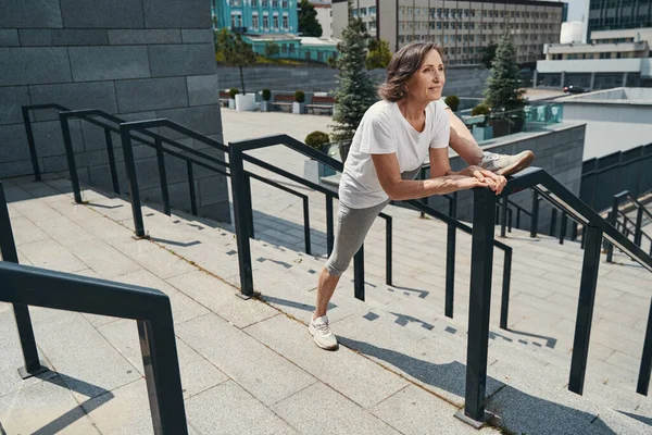 Serena senhora ativa esticando as pernas no centro da cidade — Fotografia de Stock