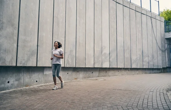 Slim zralá žena běží mezi městskou krajinou — Stock fotografie