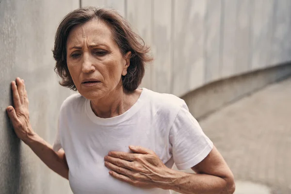 Aged sportswoman feeling pain in chest outdoors — Foto de Stock