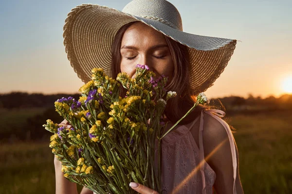 Nöjd kvinna beundrar lukten av blommor — Stockfoto