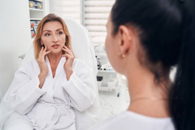 Güzel bir kadın, profesyonel biriyle güzellik prosedürlerini tartışıyor.
