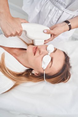 Klinikteki profesyonel yüz bakımı sırasında sakin bir kadın.