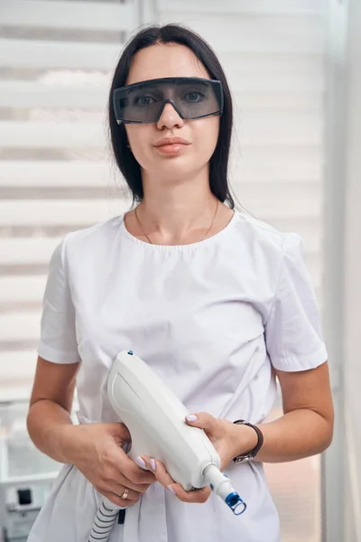 Cosmetologista feminina sorridente usando equipamentos no trabalho — Fotografia de Stock