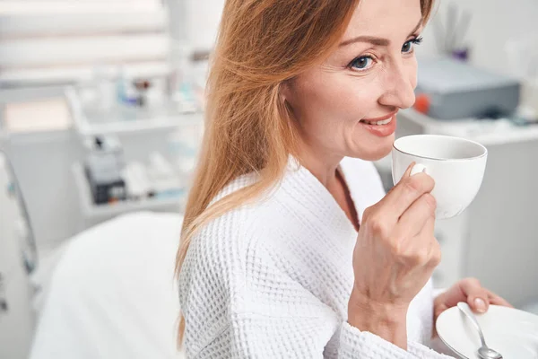 Весела жінка з кавою в клініці краси — стокове фото