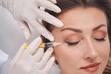 Kozmetik uzmanı kadın için güzellik enjeksiyonu yapıyor.