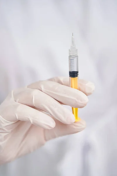 Médico con guantes protectores sosteniendo una jeringa —  Fotos de Stock