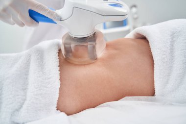 Güzellik uzmanı kadın göbeği için elektrikli süpürge kullanıyor.