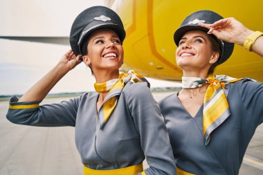 Pilot şapkalı hostesler havaalanında dikiliyor.
