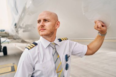 İniş yapan bir uçağın yanında duran yakışıklı pilot