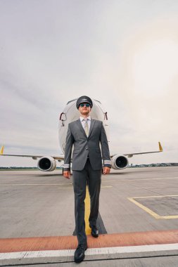 Havalimanında yürüyen zarif bir havayolu kaptanı.