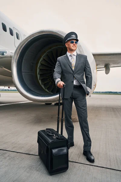 Smiling airman with his baggage at the aerodrome