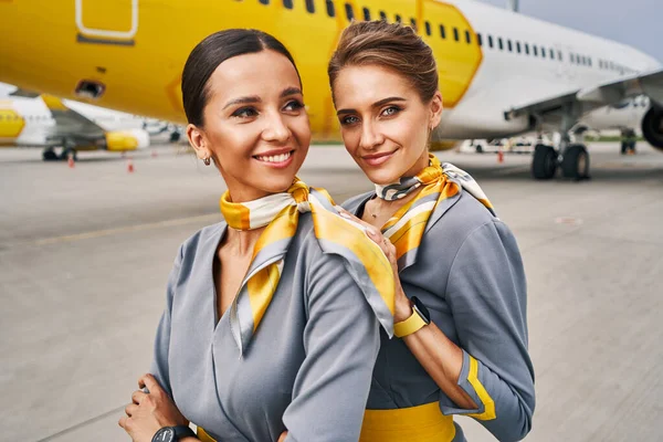 Dvě pěkné letušky v uniformách u přistávajícího letadla — Stock fotografie