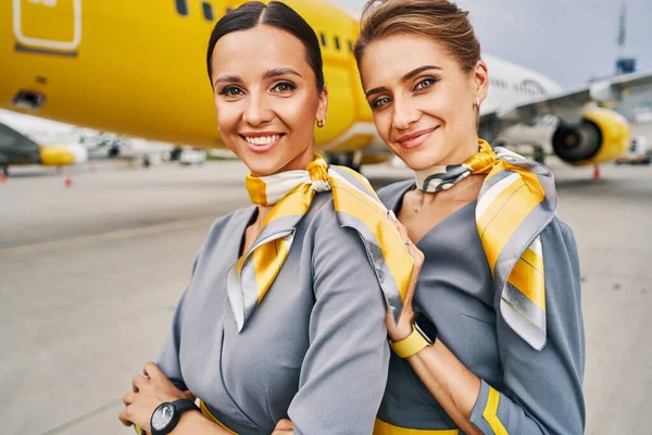 Letušky oblečené ve stylových uniformách stojící na letišti — Stock fotografie