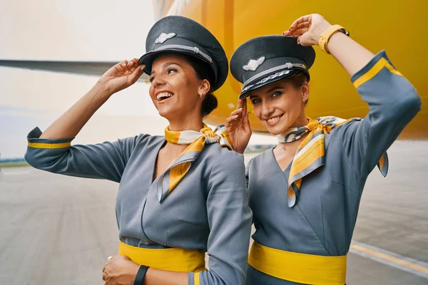 Hospedeiras aéreas alegres em uniformes por uma aeronave pousada — Fotografia de Stock