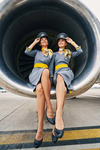 Krásné letušky v uniformách sedí se zkříženýma nohama uvnitř turbovrtulového motoru — Stock fotografie