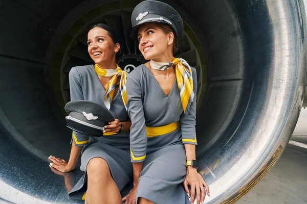 Two cute air hostesses sitting in the turbofan engine — Stock Photo, Image