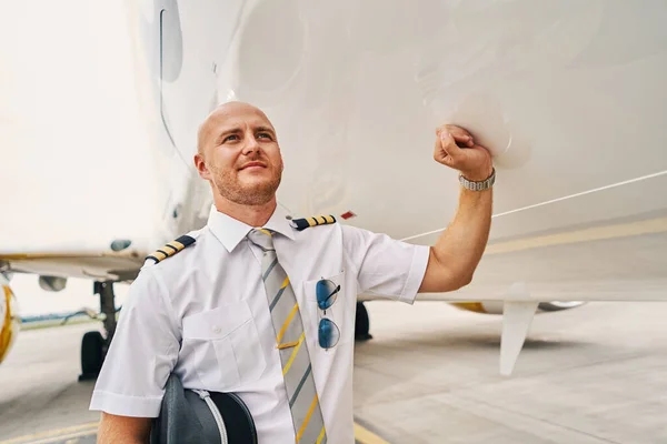 Capitaine de ligne tranquille debout près de l'avion — Photo