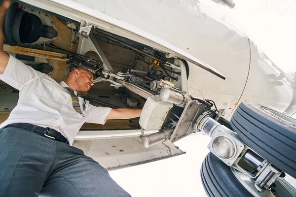 Professional aviator inspecting the aircraft undercarriage before the flight