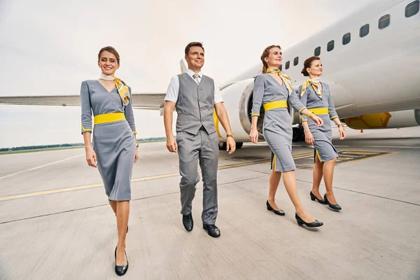 Tripulação de cabine sorridente em uniformes andando à frente — Fotografia de Stock