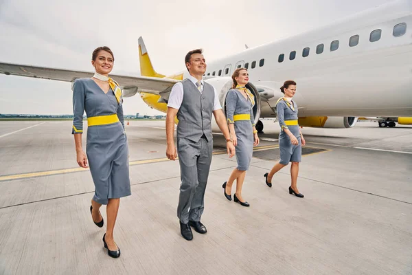 Asistente de vuelo alegre y sus colegas femeninos caminando por delante — Foto de Stock