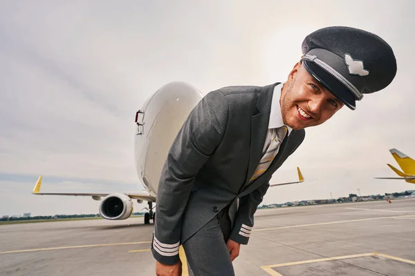 Vrolijke aantrekkelijke luchtvaartmaatschappij kapitein in uniform op de baan — Stockfoto