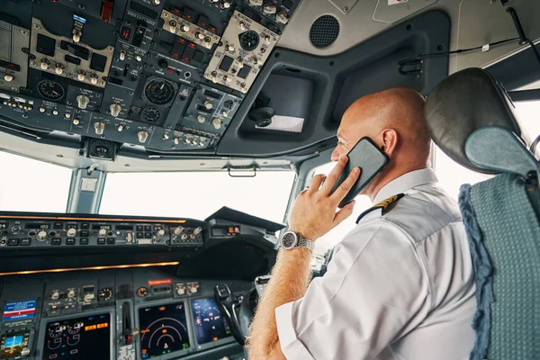 Male pilot having a phone conversation in the flight deck — Stock Photo, Image