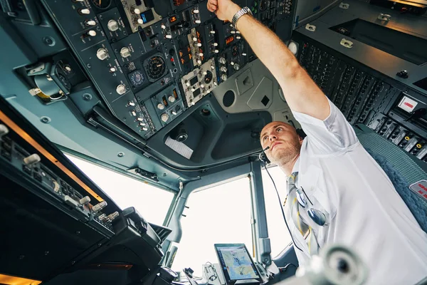 Male pilot flipping a switch on the overhead control panel — Stock Photo, Image