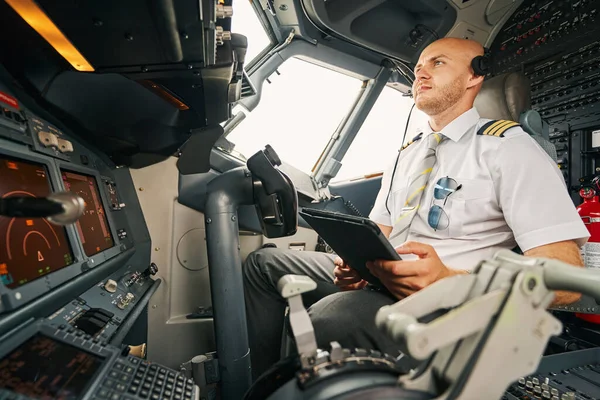 Serious male pilot staring at the aircraft control panel — Stock Photo, Image