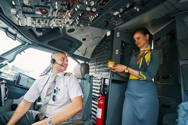 Vreugdevolle mannelijke piloot krijgt een drankje geserveerd in de cockpit — Stockfoto