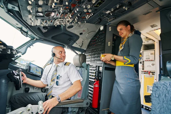 Aangename luchtvaartmaatschappij kapitein krijgt een drankje geserveerd in de cockpit — Stockfoto