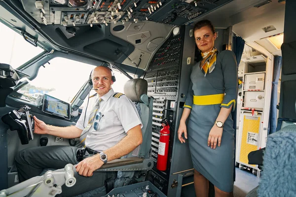 Blij piloot en een mooie stewardess poseren voor de camera — Stockfoto
