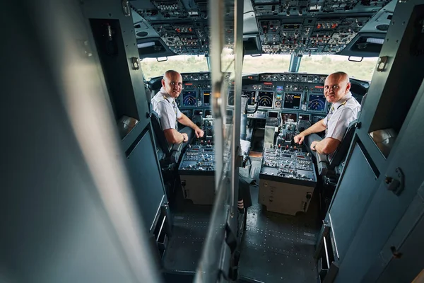 Плісе капітан авіакомпанії в навушниках, що сидять у польотній палубі — стокове фото