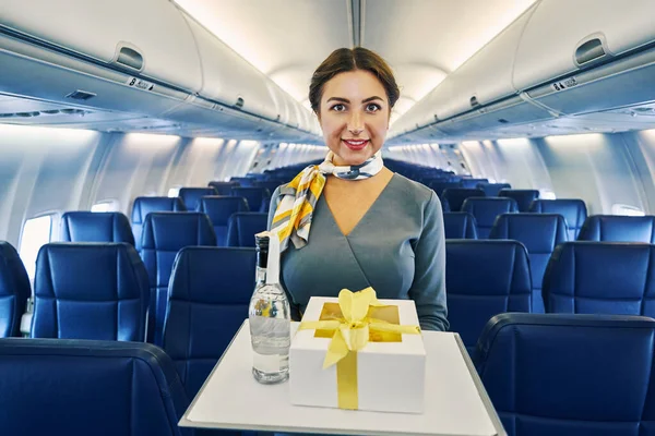 Radostná letuška s podnosem v rukou hledící před sebe — Stock fotografie