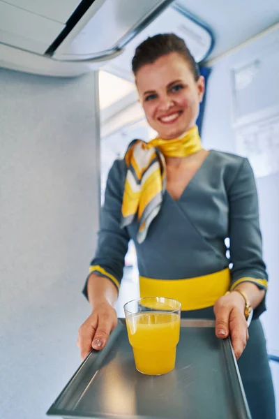 Attractive female flight attendant serving a citrus drink — Stock Photo, Image