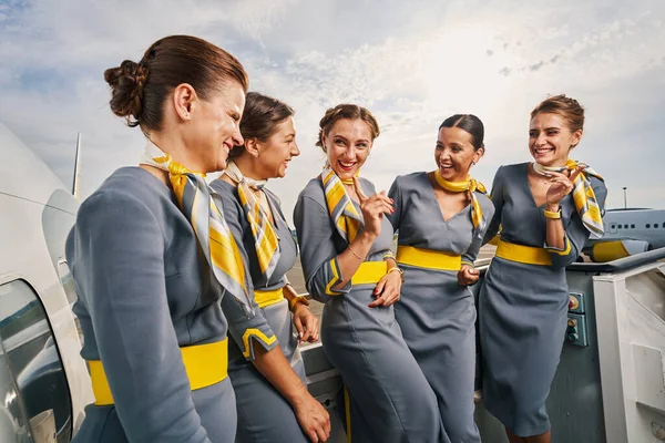 Радостные стюардессы, стоящие на посадочной лестнице во время разговора — стоковое фото