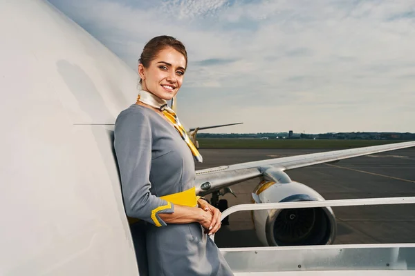 Good-looking dark-haired air hostess smiling at the camera — Stock Photo, Image