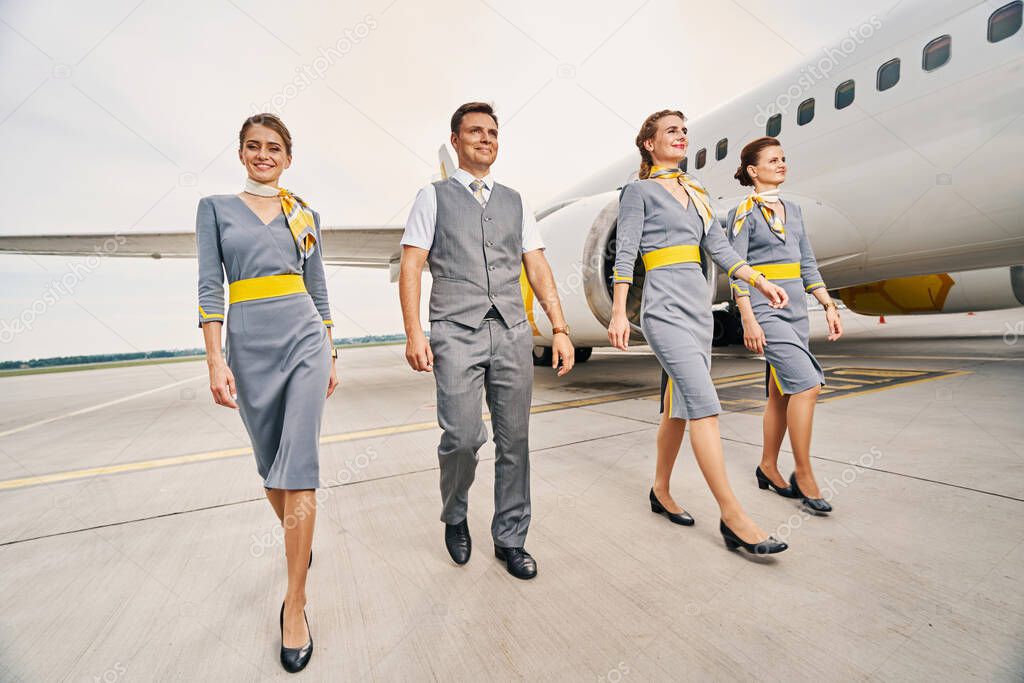 Smiling cabin crew in uniforms walking ahead