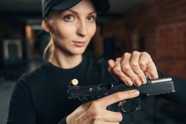 Sarışın, çekici kadın tabancayı geri çekiyor.