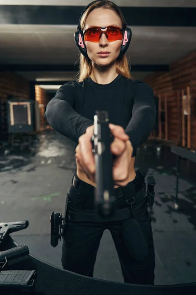 Dama con orejeras y gafas protectoras disparando un arma —  Fotos de Stock