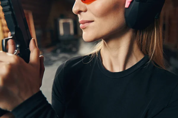 Mujer con auriculares y gafas de seguridad aprendiendo a disparar —  Fotos de Stock
