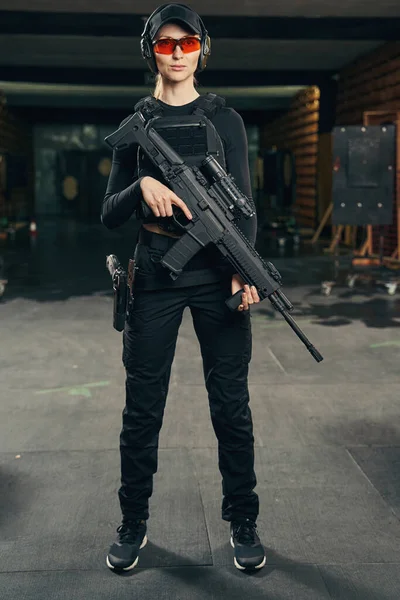 Mujer militar serena con un arma de fuego mirando hacia el futuro —  Fotos de Stock