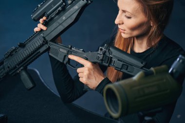 Deneyimli kadın nişancı bir silahı parçalara ayırıyor.