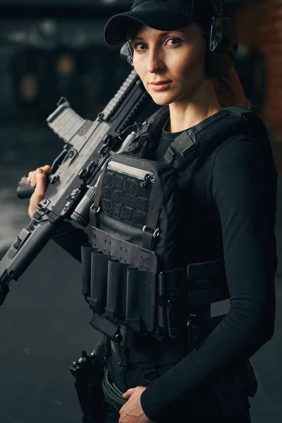 Mladá žena střelec s útočnou puškou zírá před sebe — Stock fotografie