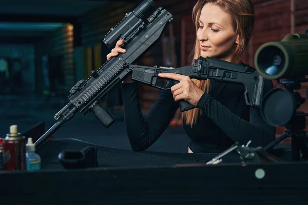 Mujer joven concentrada en desmontar el rifle de asalto —  Fotos de Stock