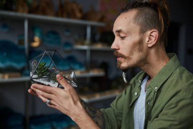 Geometrik cam teraryum tutan yakışıklı genç adam.