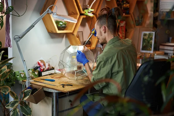 Jeune homme barbu faisant terrarium en verre dans l'atelier — Photo