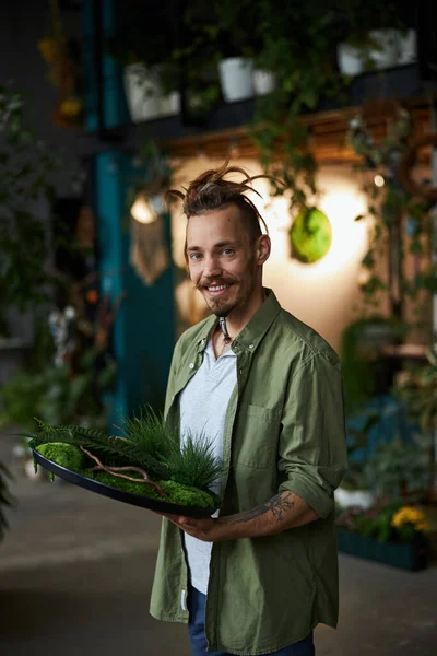 Joyful young man holding round tray with plants — Stock Photo, Image