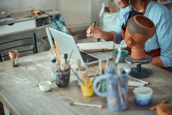 Oleiro feminino usando notebook e tomar notas na oficina de cerâmica — Fotografia de Stock