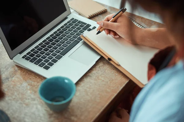 Potter femminile che scrive sul taccuino e che usa il computer portatile in officina — Foto Stock